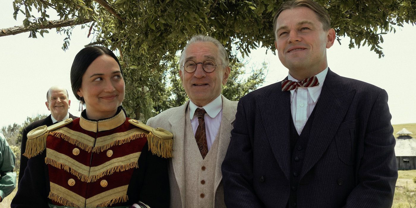 Lily Gladstone, Robert De Niro, and Leonardo DiCaprio standing together outdoors in Killers of the Flower Moon