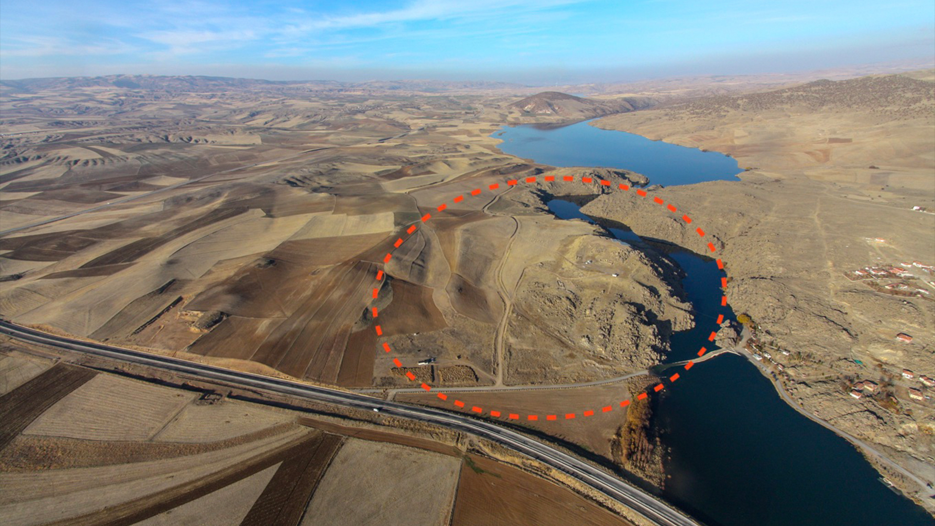 Archaeological site of Büklükale in central Turkey, surrounded by dry land with a long highway and large lake under blue sky.