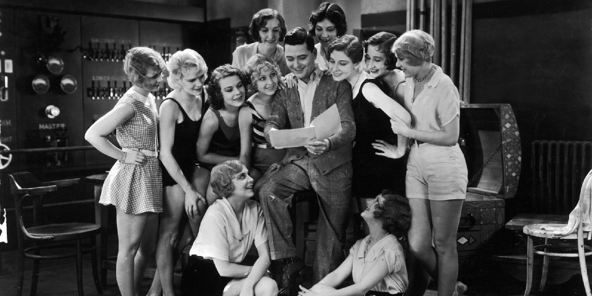 A group of people gathered and reading a paper in The Broadway Melody