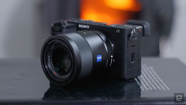 Image of a black Sony A6700 on a black textbook in front of a blurred background with an orange flash.