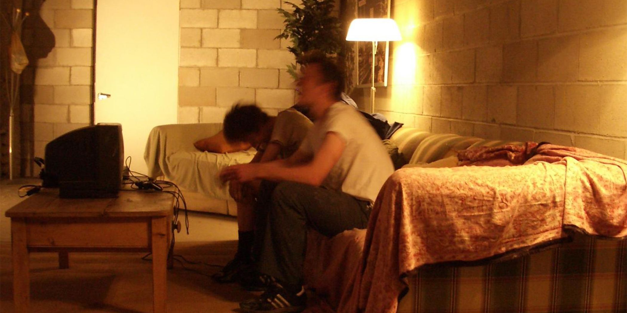 A photo of two guys blurred in motion sitting on a couch in front of a TV